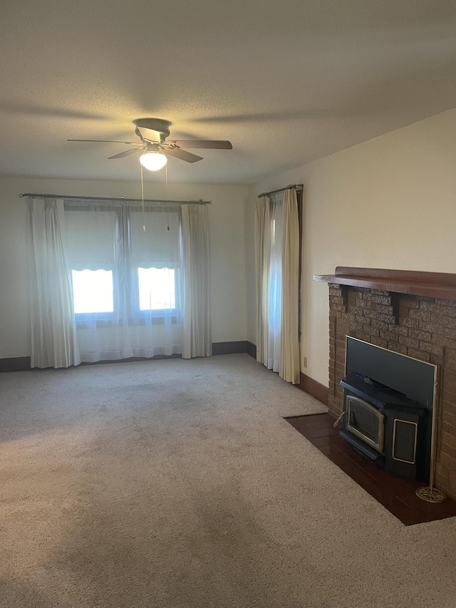 unfurnished living room featuring a textured ceiling, a wood stove, ceiling fan, and dark colored carpet