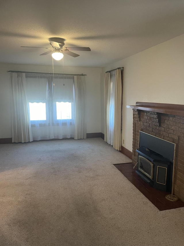 unfurnished living room with ceiling fan, dark carpet, a textured ceiling, and a wood stove