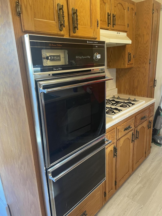 kitchen featuring double wall oven, light hardwood / wood-style floors, and white gas cooktop