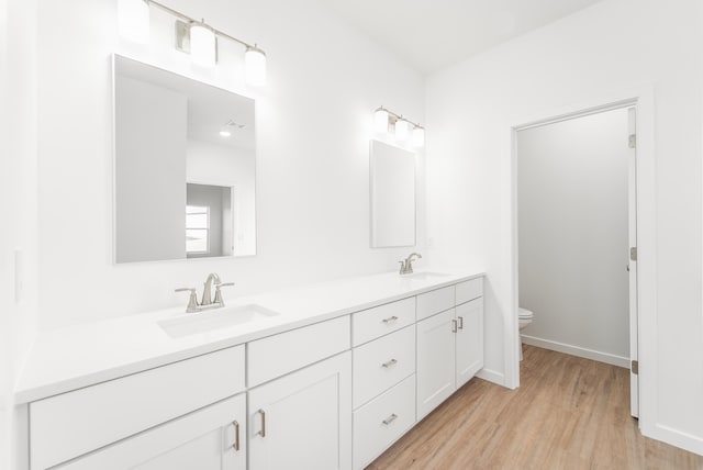 bathroom with wood-type flooring, toilet, and vanity