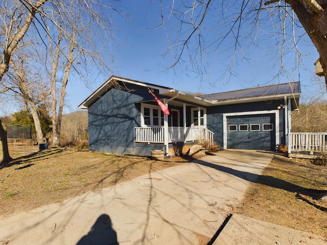 ranch-style house with a porch, a garage, and a trampoline