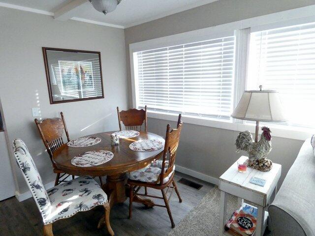 dining space with crown molding and dark wood-type flooring