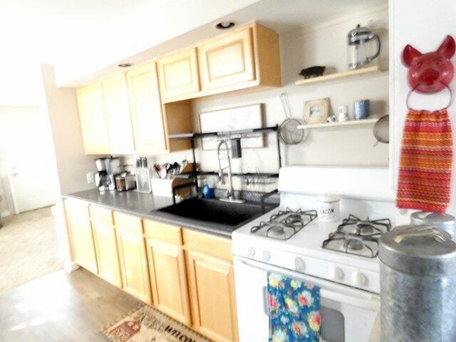 kitchen with white gas range, sink, and light brown cabinets