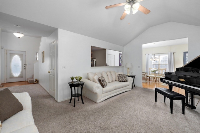 carpeted living room with ceiling fan with notable chandelier and vaulted ceiling