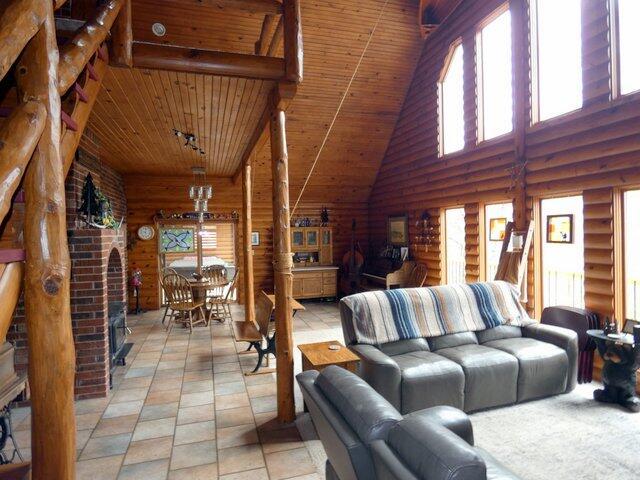 living room with a healthy amount of sunlight, rustic walls, high vaulted ceiling, and wood ceiling