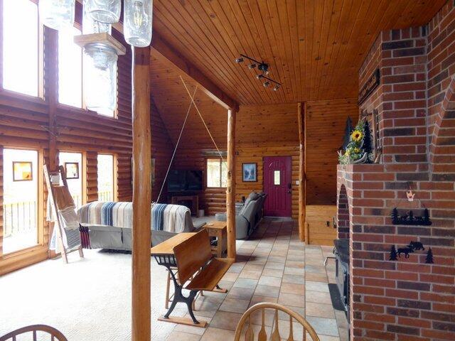 interior space with wood ceiling, log walls, plenty of natural light, and a high ceiling