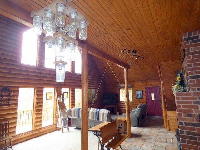 living room with wooden ceiling, rustic walls, and an inviting chandelier