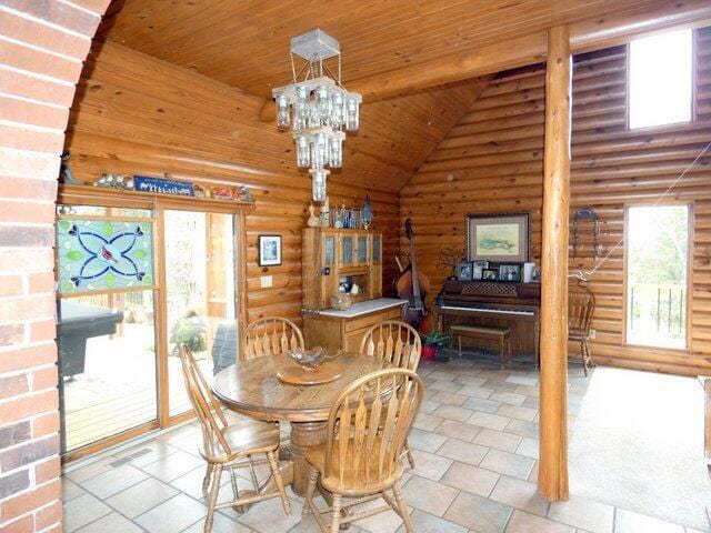 dining space with plenty of natural light, rustic walls, a chandelier, and wood ceiling