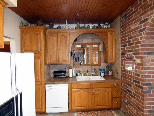 kitchen with sink, wood ceiling, white appliances, backsplash, and brick wall