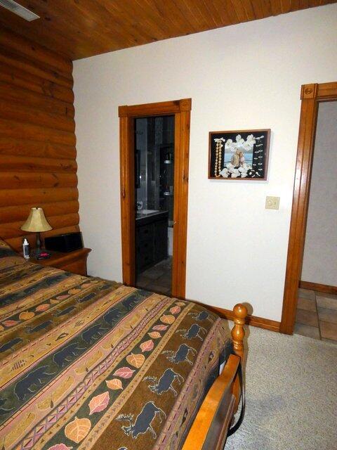 bedroom featuring wood ceiling, ensuite bath, and carpet flooring