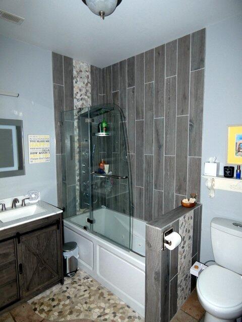 full bathroom featuring toilet, vanity, shower / bath combination with glass door, and tile patterned flooring