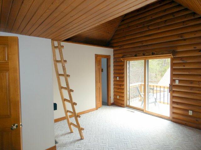 carpeted spare room with lofted ceiling, wooden ceiling, and rustic walls