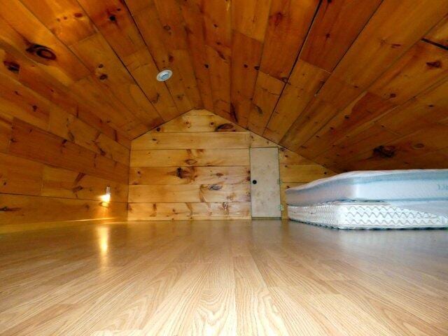 additional living space with lofted ceiling, wooden ceiling, and wooden walls