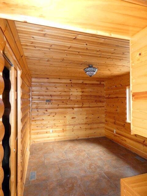 unfurnished room with log walls and wood ceiling