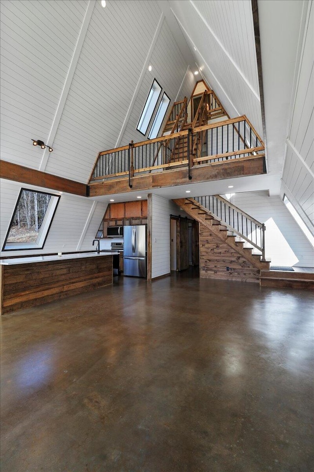 unfurnished living room with a skylight and high vaulted ceiling