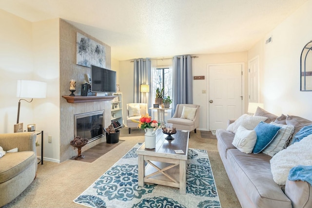 living room featuring a large fireplace, light carpet, and a textured ceiling