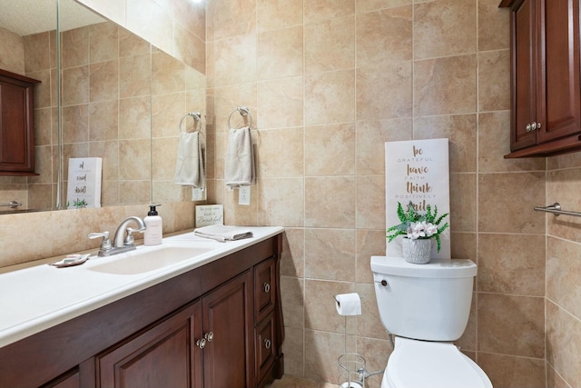 bathroom with vanity, toilet, and tile walls