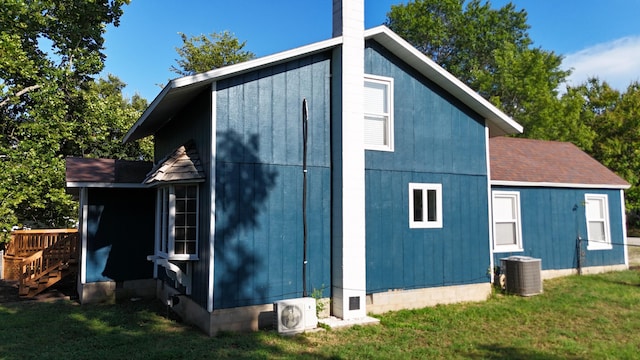 exterior space with ac unit, a lawn, and central air condition unit