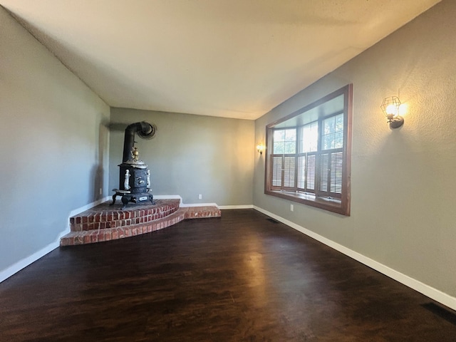 unfurnished living room featuring dark hardwood / wood-style floors and a wood stove