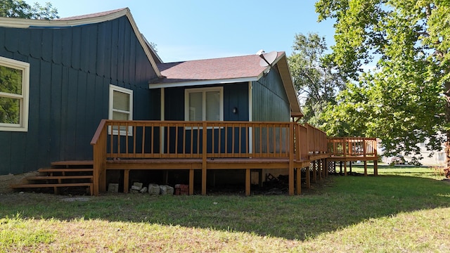 rear view of house with a wooden deck and a lawn