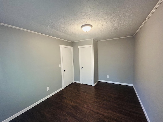 empty room with crown molding, dark hardwood / wood-style floors, and a textured ceiling