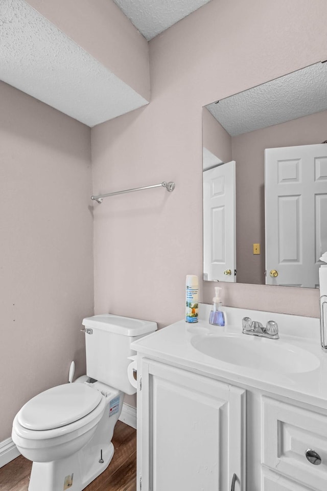 bathroom featuring vanity, hardwood / wood-style flooring, toilet, and a textured ceiling