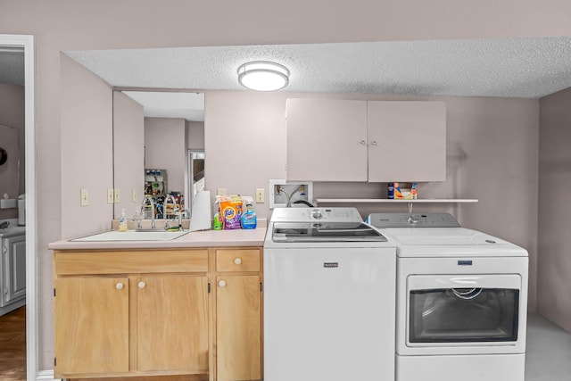 washroom with sink, washer and dryer, and a textured ceiling