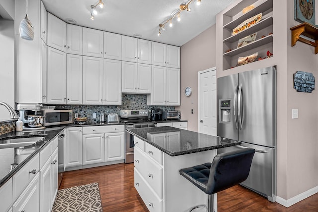 kitchen featuring sink, appliances with stainless steel finishes, dark hardwood / wood-style floors, white cabinets, and a kitchen island