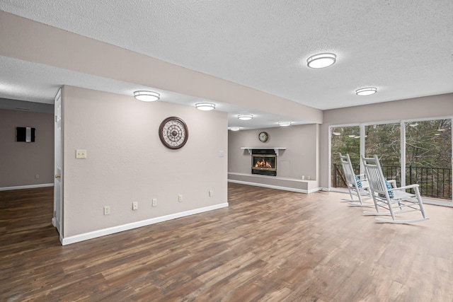 unfurnished living room featuring a textured ceiling and dark hardwood / wood-style flooring