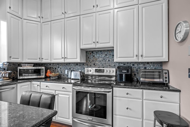 kitchen with backsplash, appliances with stainless steel finishes, dark stone counters, and white cabinets