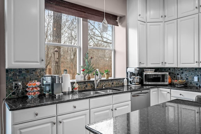 kitchen with sink, tasteful backsplash, dark stone countertops, pendant lighting, and white cabinets