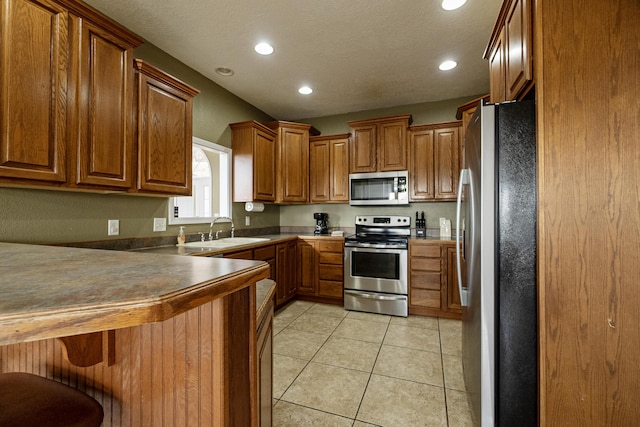 kitchen with sink, light tile patterned floors, a breakfast bar area, and stainless steel appliances