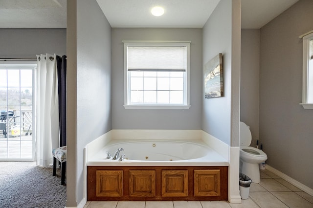 bathroom featuring toilet, tile patterned floors, and a tub to relax in