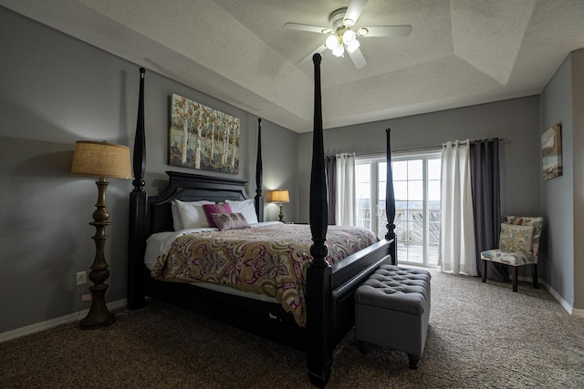 carpeted bedroom with ceiling fan, a tray ceiling, and a textured ceiling