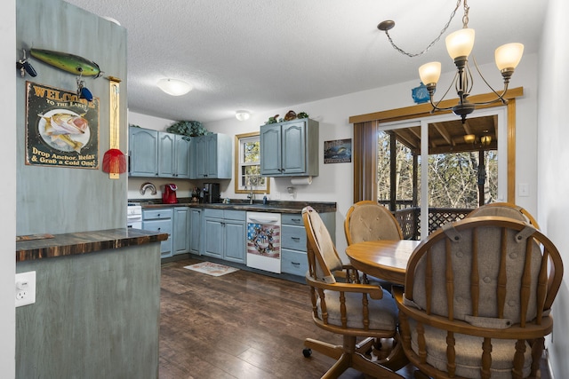 kitchen featuring pendant lighting, dark wood-type flooring, an inviting chandelier, white dishwasher, and a textured ceiling