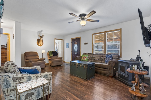 living room with dark wood-type flooring, ceiling fan, a textured ceiling, and a wood stove