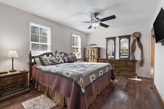 bedroom with dark wood-type flooring, a textured ceiling, and ceiling fan