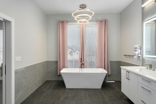 bathroom featuring vanity, a tub, tile walls, and a chandelier