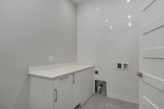 clothes washing area with cabinets, electric dryer hookup, tile walls, and light tile patterned floors