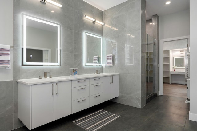 bathroom with tile patterned floors, vanity, a shower with shower door, and tile walls