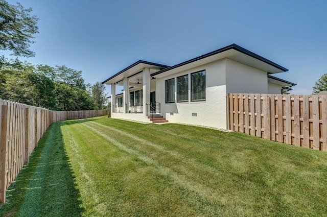 rear view of house with ceiling fan and a yard