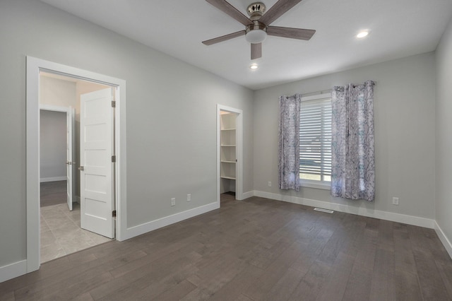 unfurnished bedroom with wood-type flooring, a walk in closet, and ceiling fan