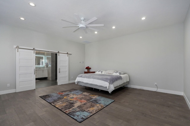 bedroom featuring dark hardwood / wood-style floors, ceiling fan, ensuite bathroom, and a barn door