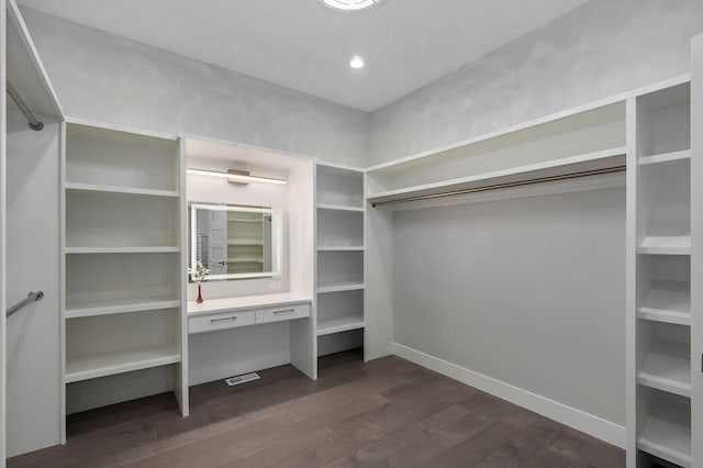 walk in closet featuring dark hardwood / wood-style floors and built in desk