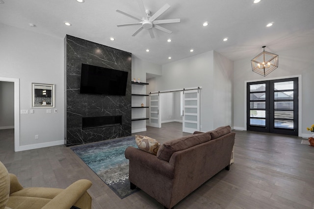 living room with a fireplace, hardwood / wood-style flooring, ceiling fan, a barn door, and french doors