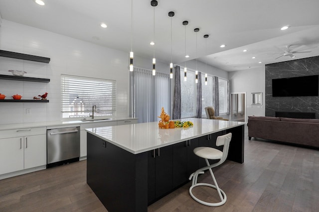 kitchen featuring sink, decorative light fixtures, dishwasher, a kitchen island, and white cabinets