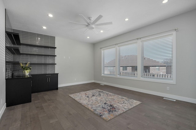 unfurnished living room with dark wood-type flooring and ceiling fan