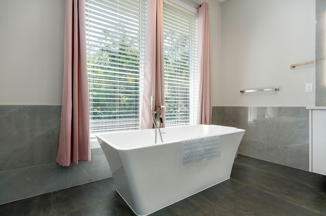 bathroom with tile patterned floors, a tub to relax in, and tile walls