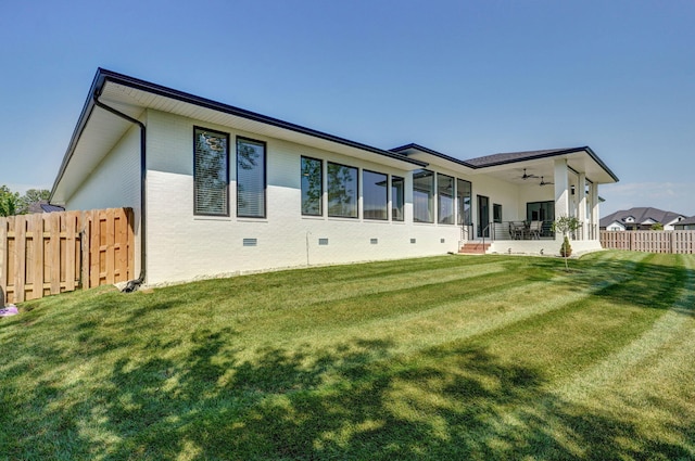 back of house with ceiling fan and a lawn