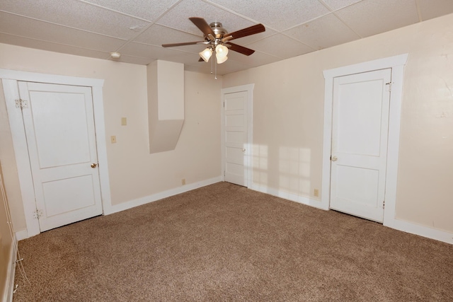 carpeted empty room with ceiling fan and a drop ceiling